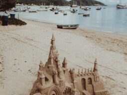 sand castle on tropical seashore near floating boats