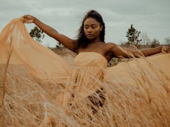 a woman in a yellow dress is standing in a field