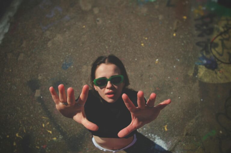 woman in sunglasses posing with hands raised