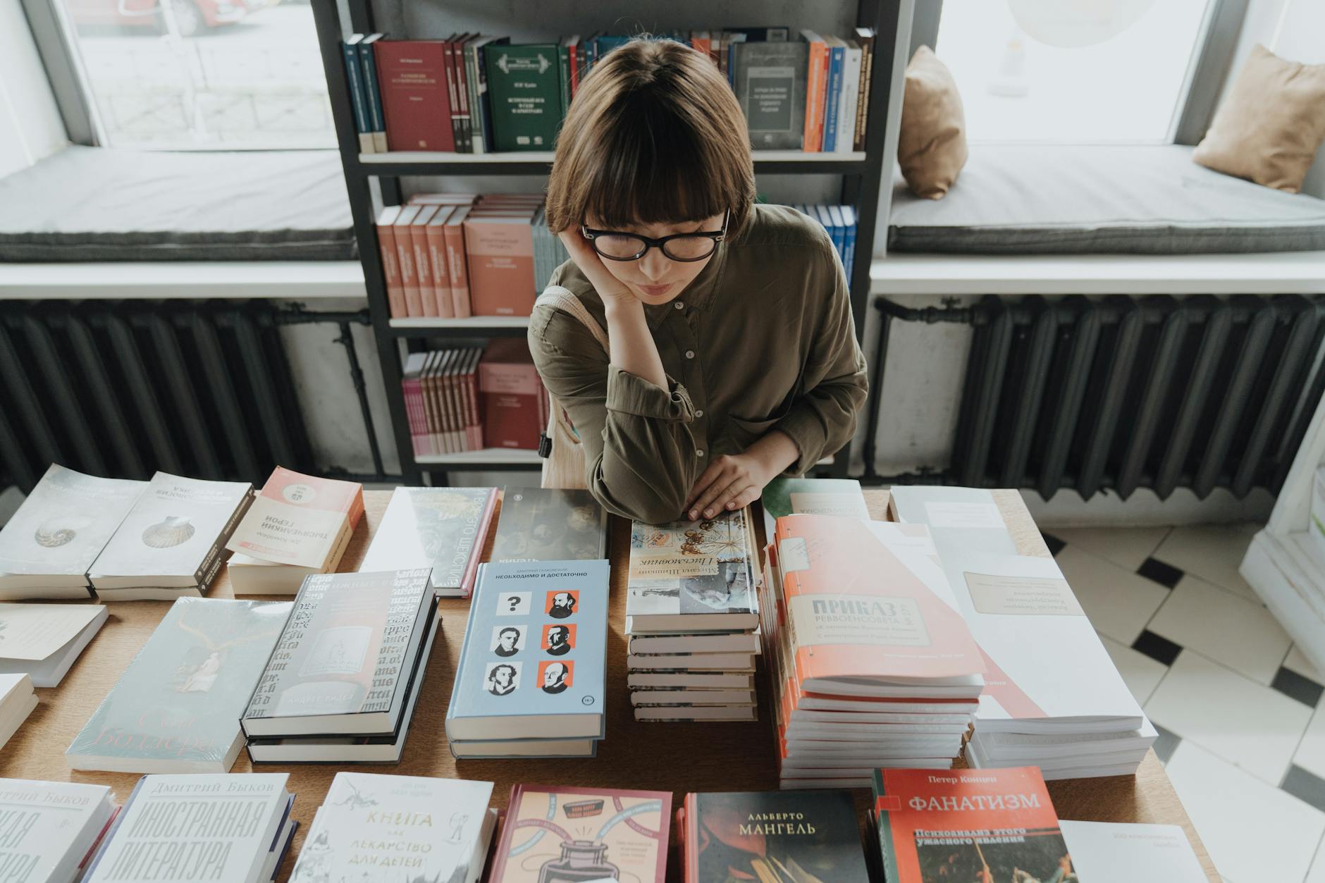 woman in brown jacket sitting on chair reading book