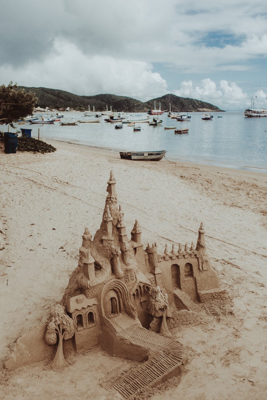 sand castle on tropical seashore near floating boats