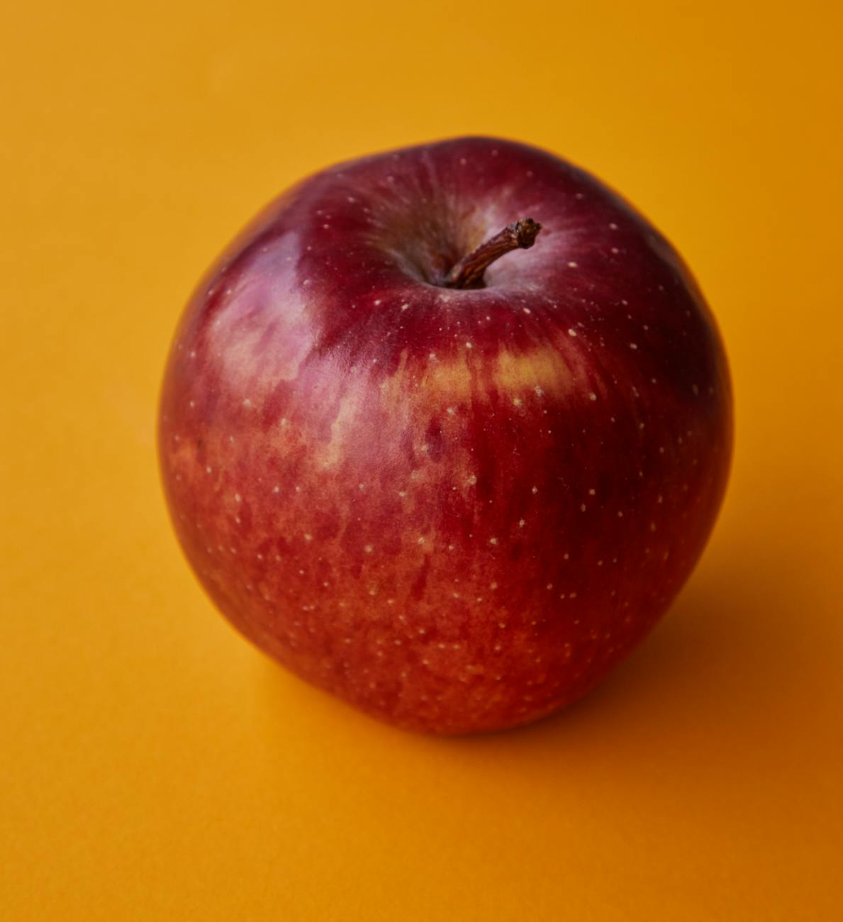 tasty red apple served on orange table