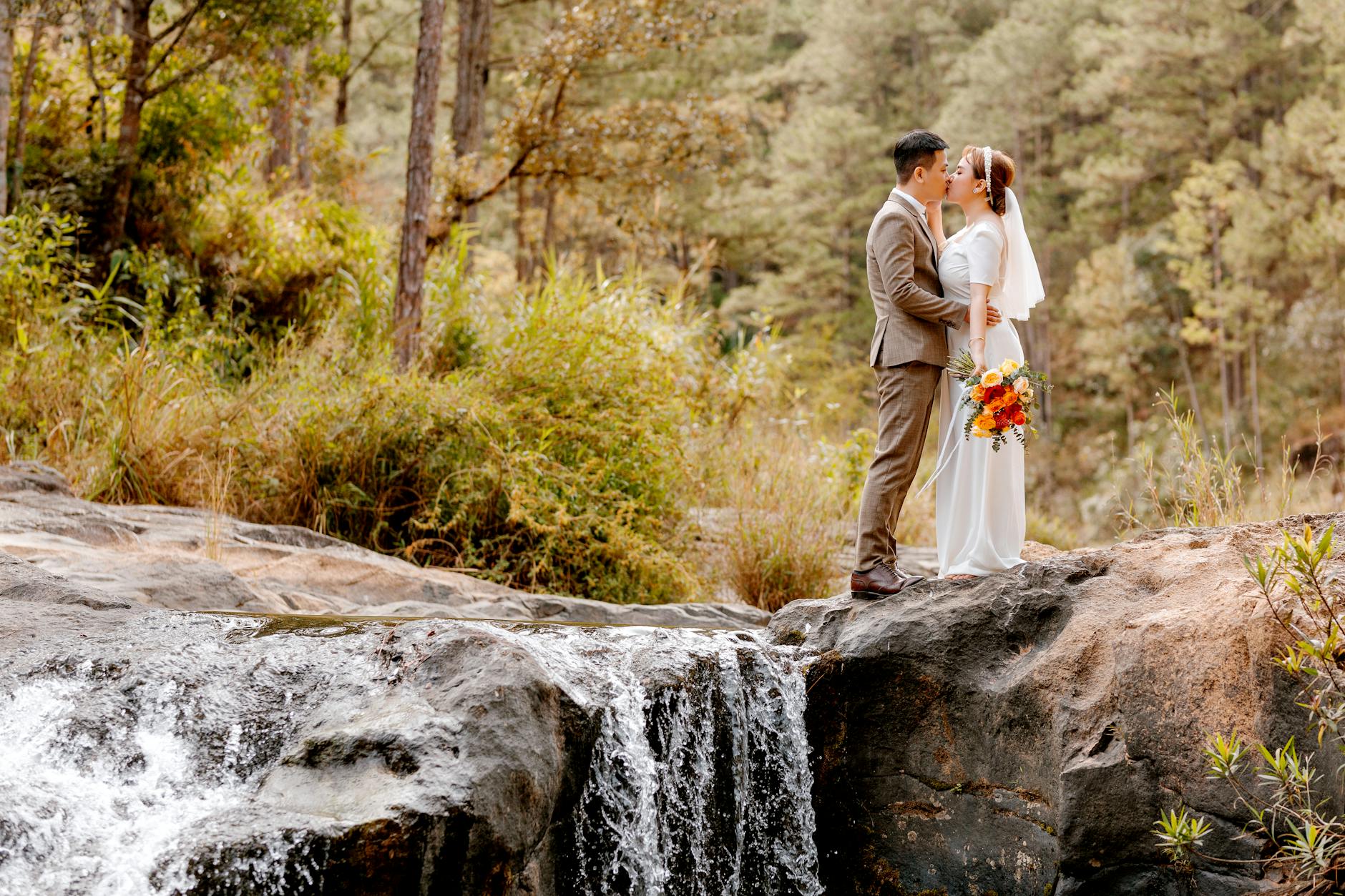 bride and groom standing on rock