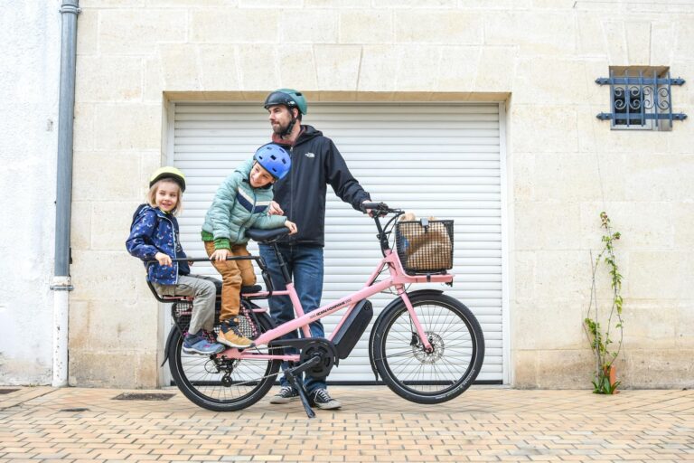 family riding pink cargo bike in paris