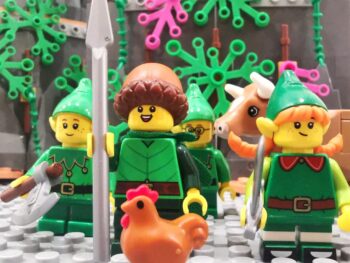 Miniature toy elf figures, a cow and a chicken fixed on a board, Lego style