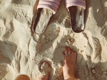 person standing on sand in front slide sandals