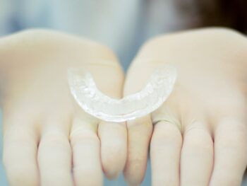 a clear retainer on a person s hands wearing gloves