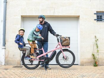 family riding pink cargo bike in paris