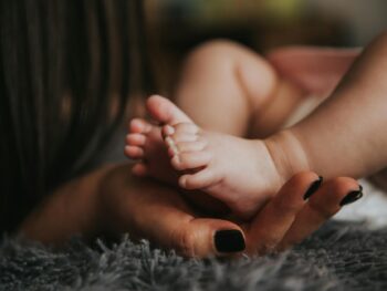 person holding baby s feet in selective focus photography