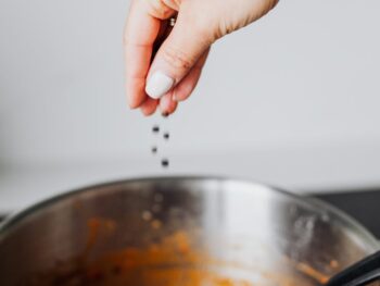 photo of a person putting black pepper into a pot