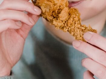 hungry woman biting fried delicious chicken