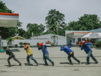 five men pulling black rope